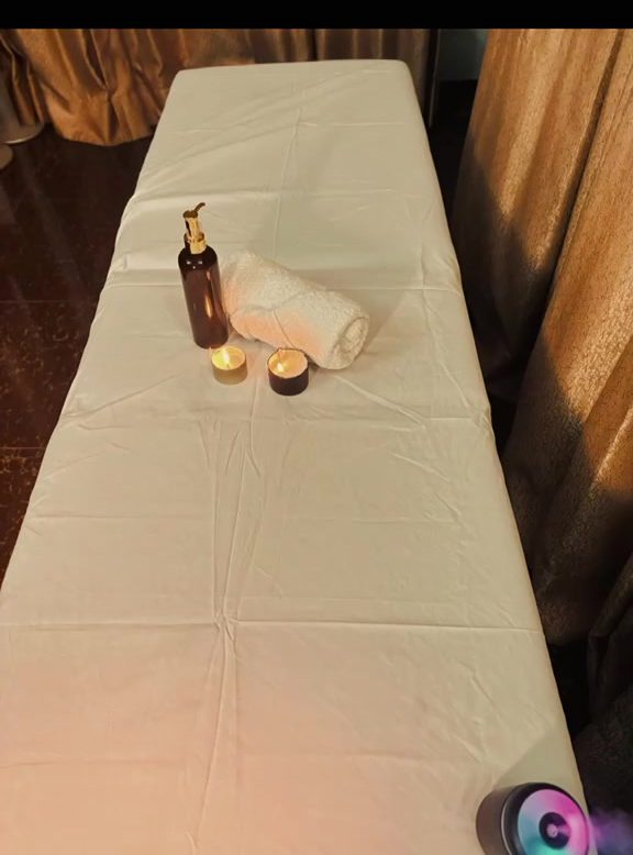 A prepared massage table with towel, candle and oil